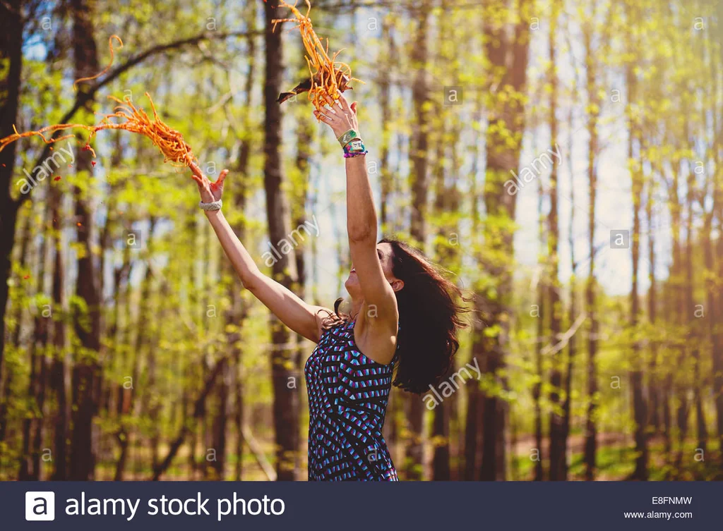 woman throwing spaghetti in a forest